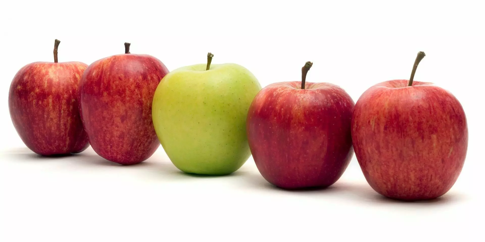 four red apples in a row with a green apple in the middle